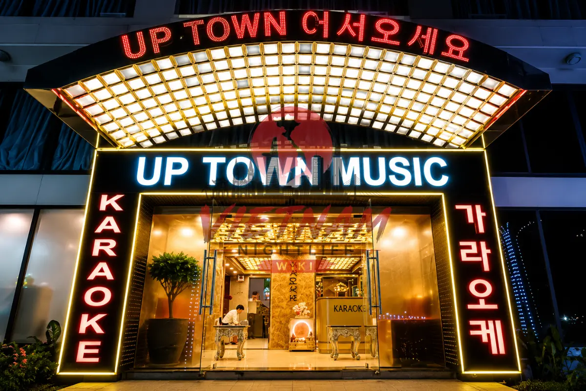 업타운 가라오케 야간 입구 — 'UP TOWN 어서오세요' 화려한 네온 아치 간판과 황금빛 로비 전경