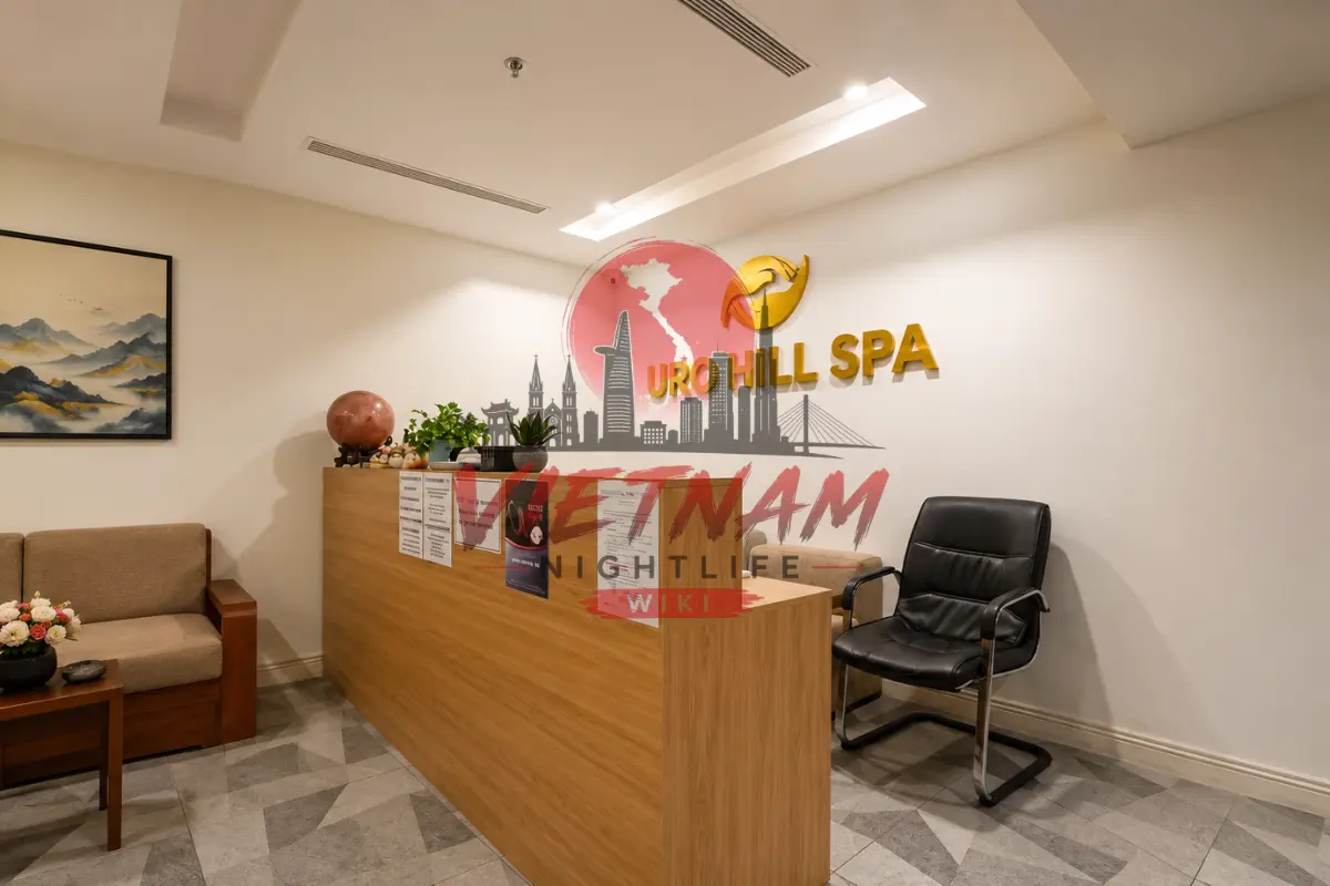 다낭 청룡열차 스파 팜반동 메인 카운터 — 우드 데스크 리셉션과 벽면 URO HILL SPA 골드 양각 엠블럼 상징물 및 소파 라운지