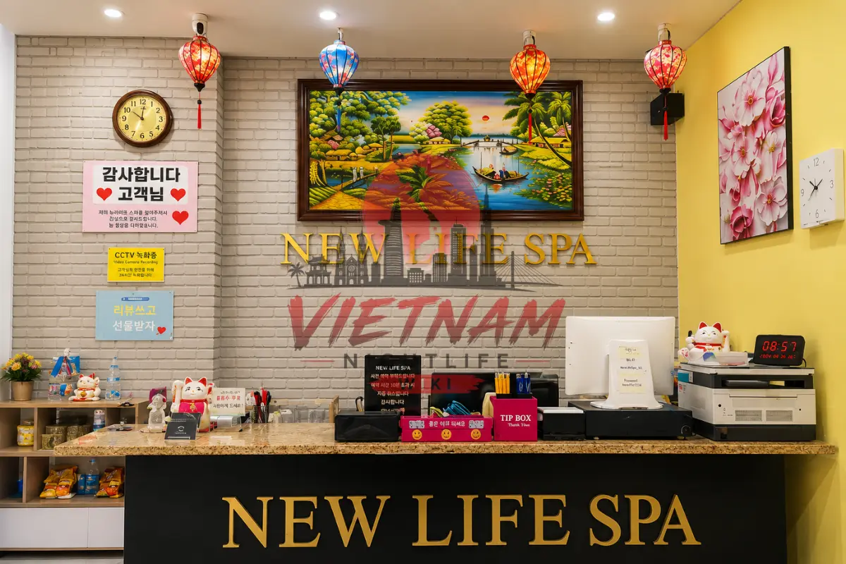 다낭 뉴라이프 스파 1층 메인 안내 카운터 — NEW LIFE SPA 골드 레터링 카운터와 베트남 전통등 조명, 마네키네코 복고양이 및 풍경화 액자