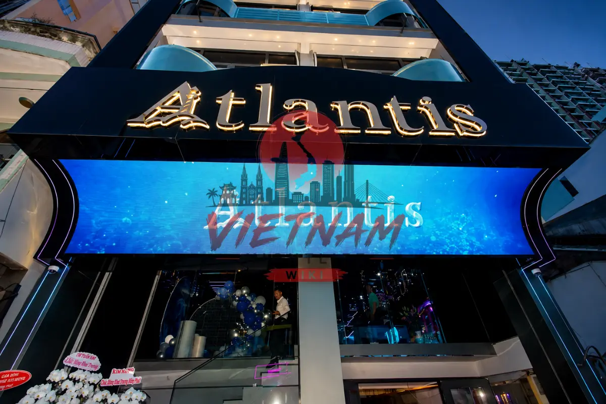 호치민 아틀란티스 가라오케 1군 데탐 거리 외관 야경 — 블랙 바탕 Atlantis 골드 네온 간판·블루 LED 사이니지